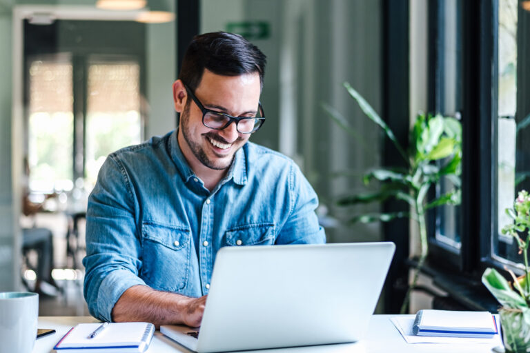 Smiling,Young,Entrepreneur,Working,On,Laptop,At,Table.,Confident,Male