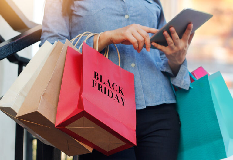 Woman,Using,Tablet,And,Holding,Black,Friday,Shopping,Bag,While