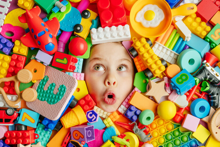 Funny,Surprised,Little,Girl,Lying,In,The,Chaos,Of,Toys.