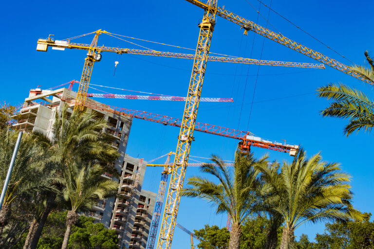 Building,Yellow,Crane,On,The,Background,Of,Tropical,Palm,Trees