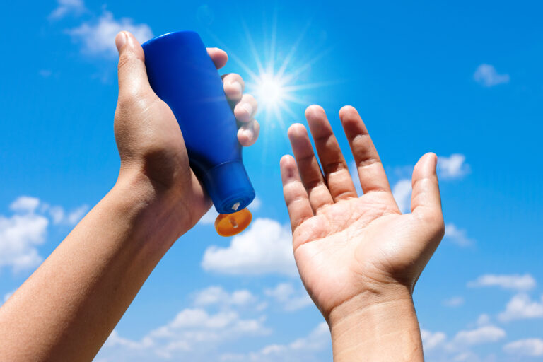 Hand,Of,Female,Holding,Sunscreen.,Very,Sun,Light,Sky,Background.health