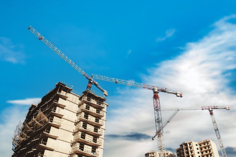 Construction,Cranes,Work,On,Creation,Site,Against,Blue,Sky,Background.
