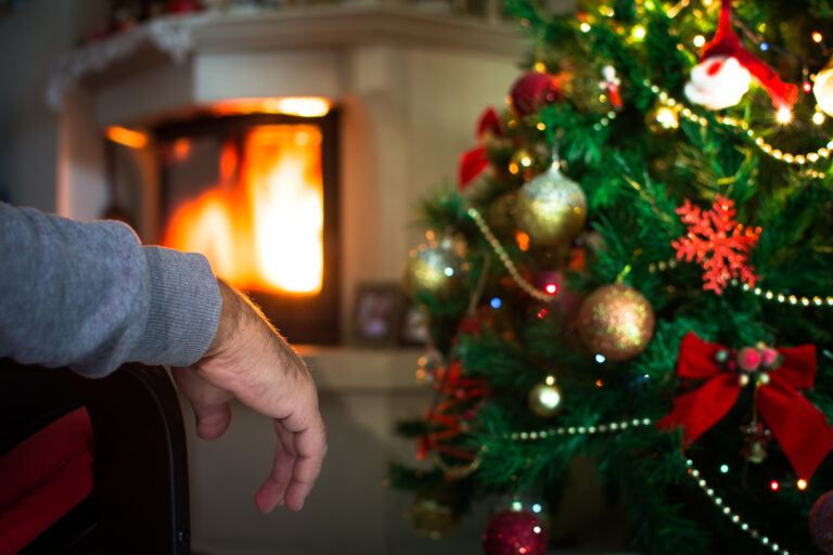 Lonely,Man's,Hand,In,Front,Of,The,Fireplace,With,Christmas
