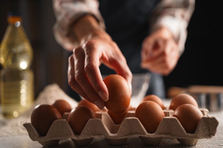 Female,Hands,Picking,Up,Egg,From,Carton,While,Preparing,Ingredients