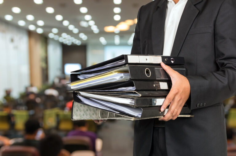 Businessman,Is,Holding,Many,Document,Folders,On,Abstract,Blurred,Photo