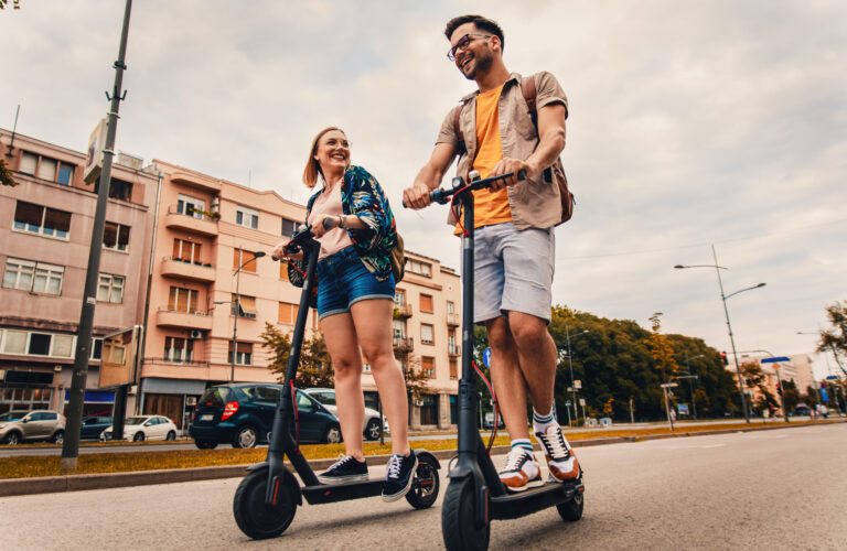 Young,Couple,On,Vacation,Having,Fun,Driving,Electric,Scooter,Through