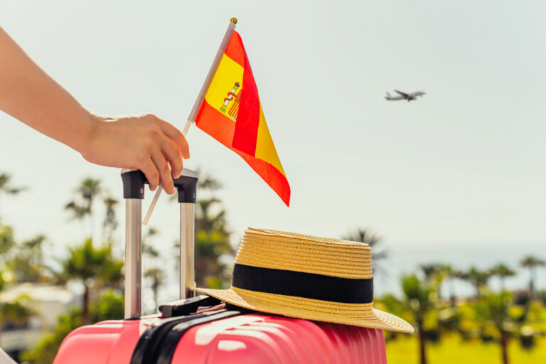 Woman,With,Pink,Suitcase,,Hat,And,Spain,Flag,Standing,On