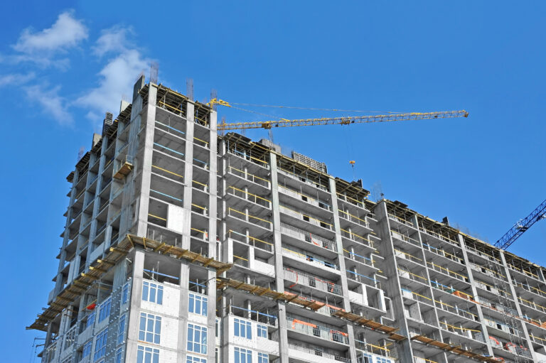 Crane,And,Building,Construction,Site,Against,Blue,Sky