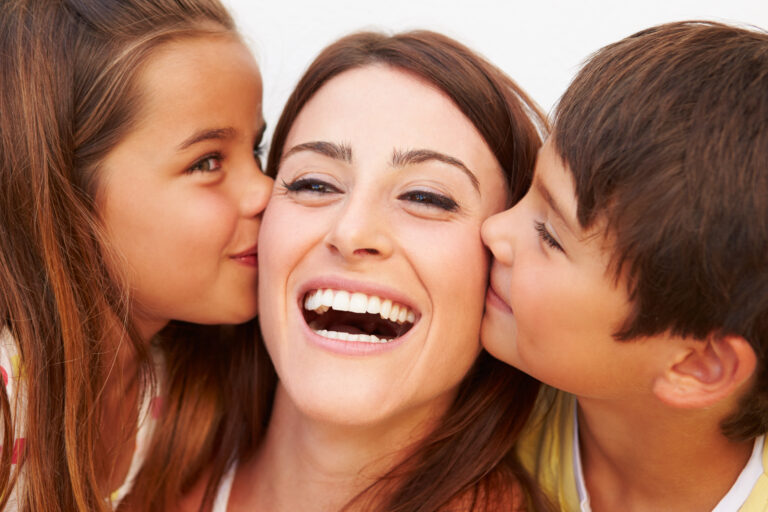 Portrait,Of,Hispanic,Children,Kissing,Mother