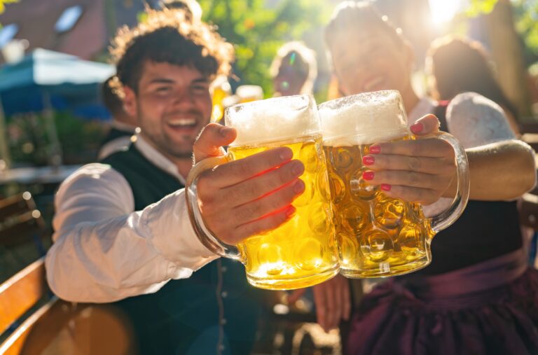 Two,People,In,Traditional,Tracht,Clinking,Beer,Mugs,And,Smiling
