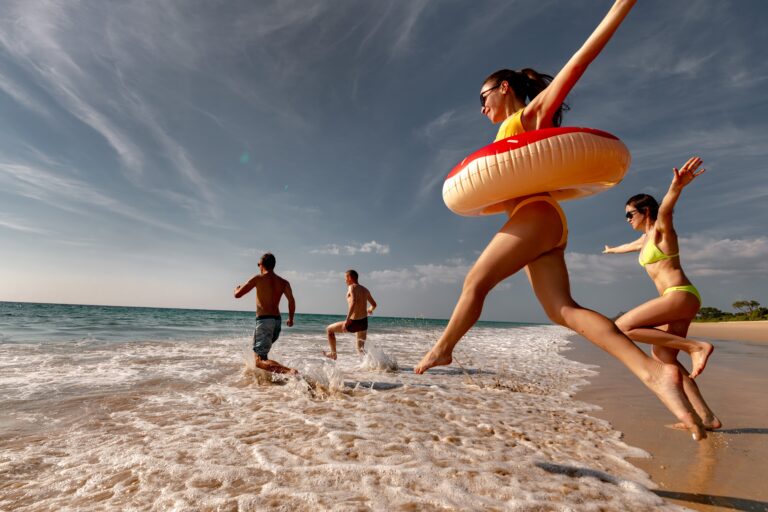 Happy,Friends,Runs,And,Jumps,With,Inflatable,Donuts,To,Sea