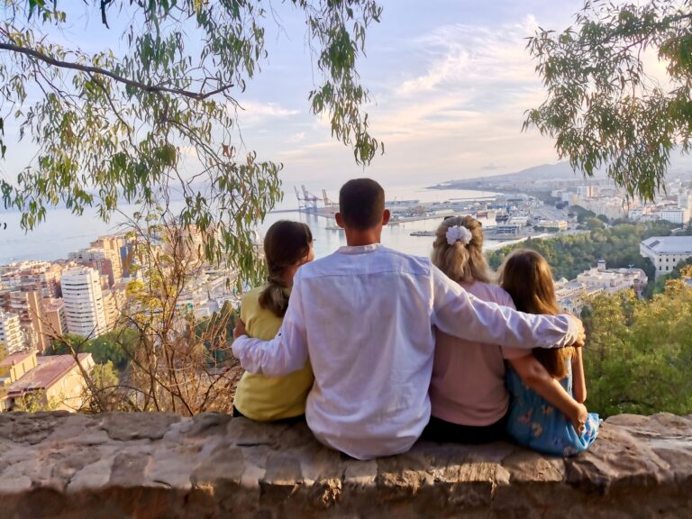 Rear,View,Of,A,Family,Sitting,Together,On,A,Hilltop