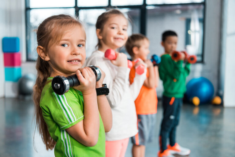 Selective,Focus,Of,Multiethnic,Children,Lined,Up,,Holding,Dumbbells,And