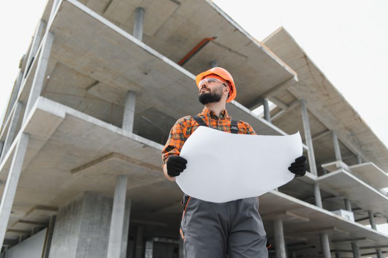Construction,Worker,In,Hard,Hat,And,Safety,Glasses,Holding,Blueprint