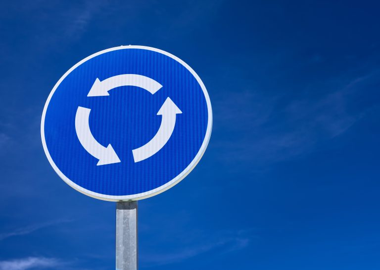 Detail,Of,A,Roundabout,Sign,Over,A,Blue,Sky
